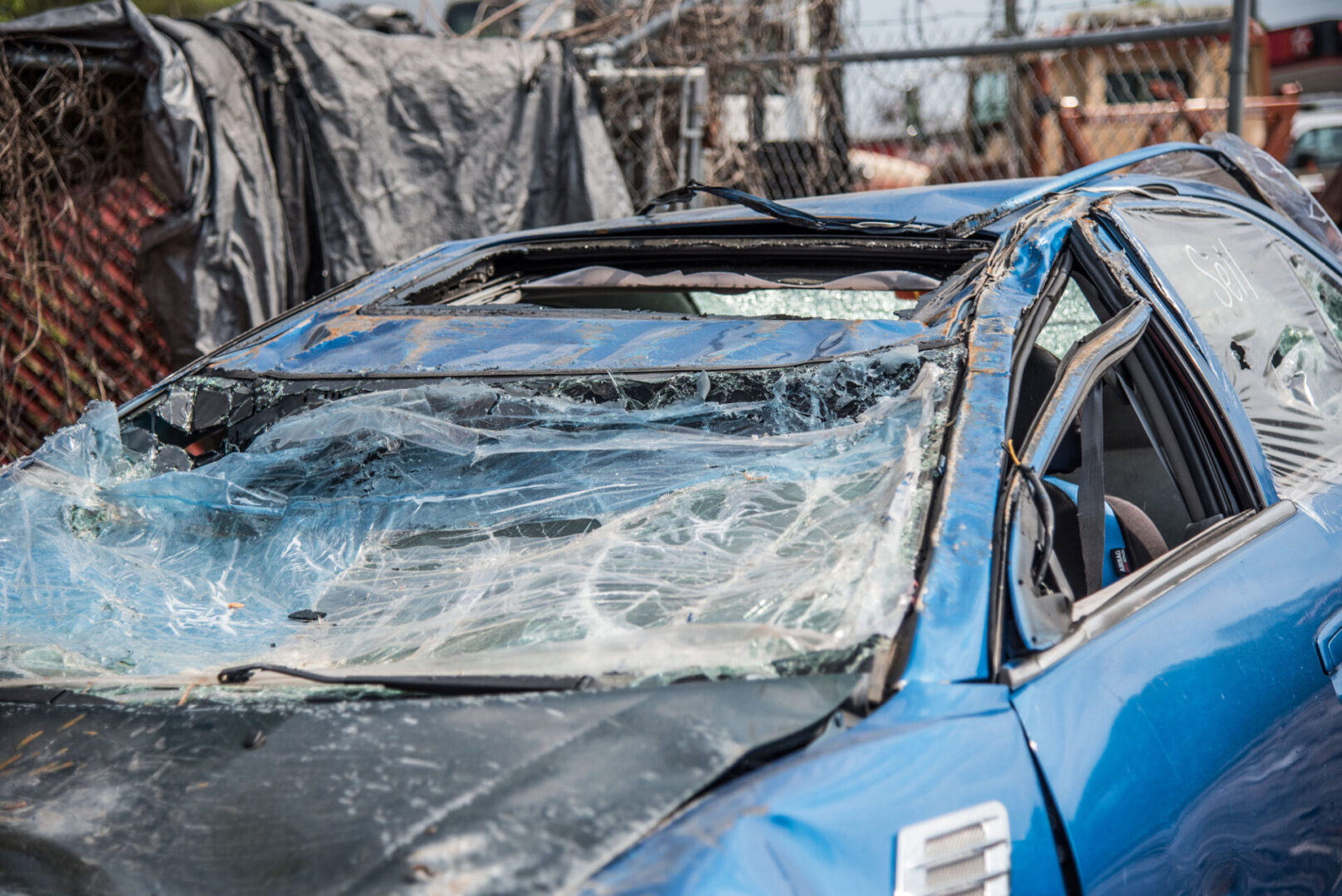 Blue car with smashed windshield and roof
